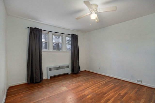 spare room featuring radiator, dark wood-type flooring, and ceiling fan