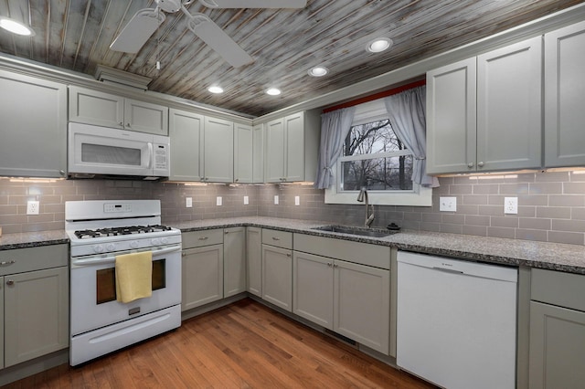 kitchen featuring white appliances, sink, hardwood / wood-style flooring, tasteful backsplash, and light stone counters