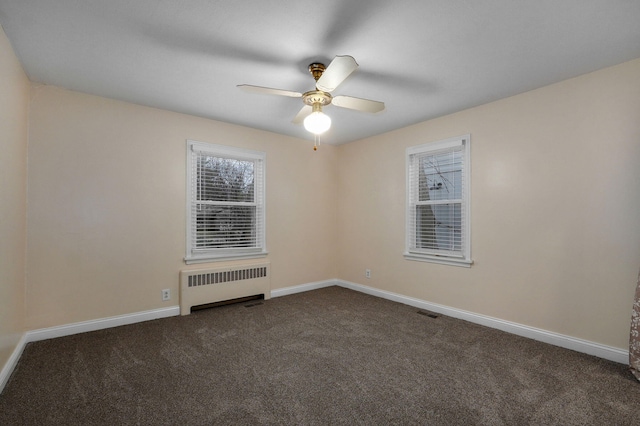 carpeted spare room featuring radiator heating unit and ceiling fan