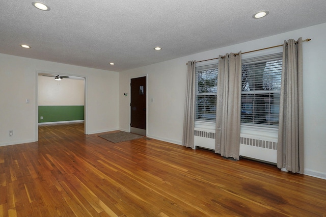 unfurnished room featuring hardwood / wood-style floors, radiator heating unit, and a textured ceiling