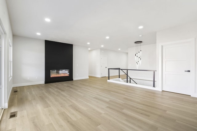 unfurnished living room featuring light wood-type flooring and a fireplace