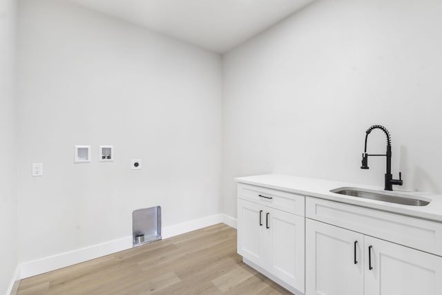 clothes washing area with hookup for a washing machine, sink, light hardwood / wood-style flooring, and hookup for an electric dryer