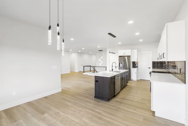 kitchen featuring sink, an island with sink, decorative light fixtures, white cabinets, and appliances with stainless steel finishes