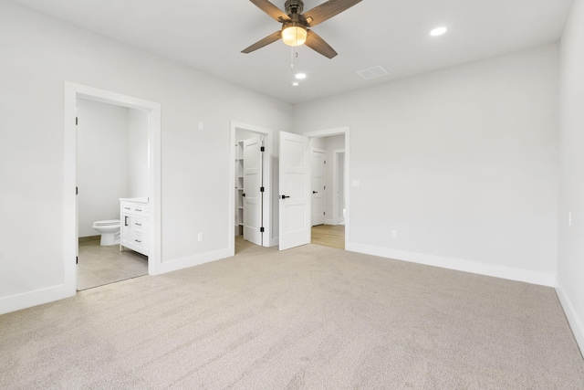 unfurnished bedroom featuring ceiling fan, a spacious closet, connected bathroom, light colored carpet, and a closet