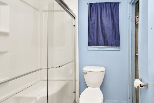 bathroom featuring toilet and a shower with door