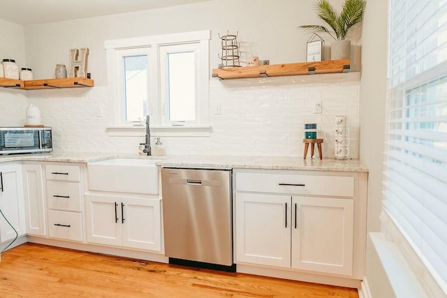 kitchen featuring tasteful backsplash, light stone counters, stainless steel appliances, sink, and white cabinets