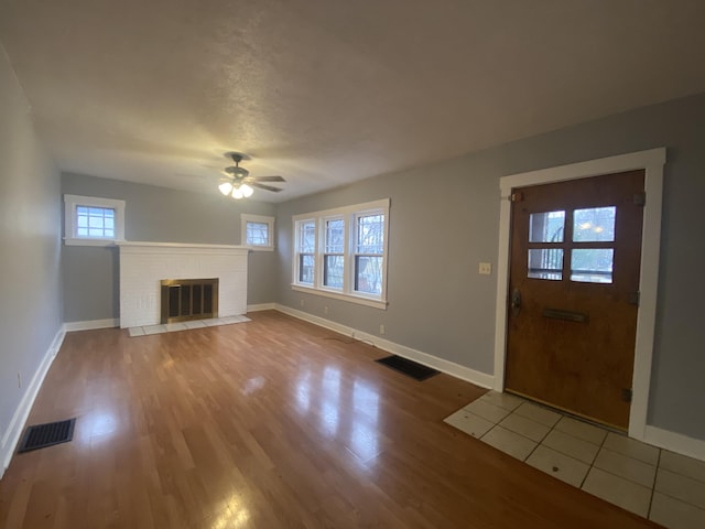 unfurnished living room featuring ceiling fan, light wood-type flooring, and a fireplace