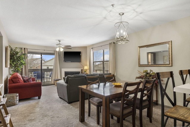 dining space featuring carpet flooring and ceiling fan with notable chandelier