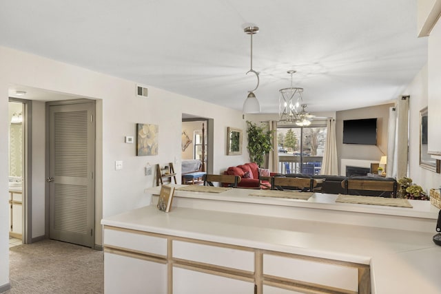 kitchen featuring light carpet, decorative light fixtures, and an inviting chandelier