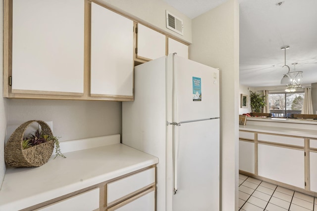 kitchen featuring white cabinets, pendant lighting, white fridge, and a chandelier