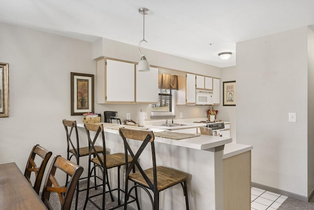 kitchen featuring hanging light fixtures, light tile patterned floors, stainless steel range, a kitchen bar, and kitchen peninsula