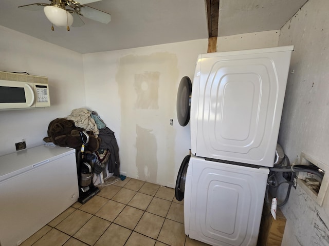 washroom featuring stacked washer / dryer, ceiling fan, and light tile patterned floors