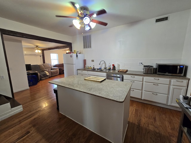 kitchen with sink, stainless steel appliances, dark wood-type flooring, a kitchen island, and white cabinets