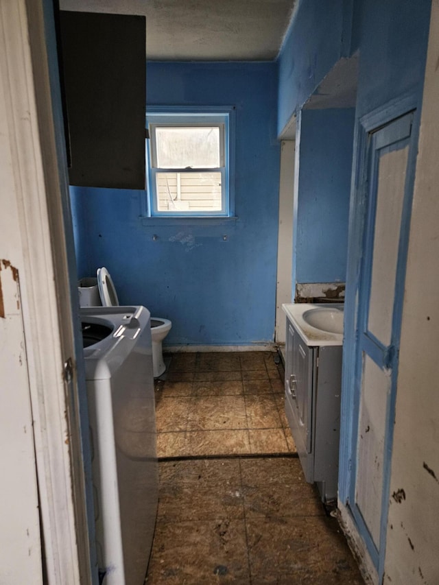 bathroom featuring washer / clothes dryer, vanity, and toilet