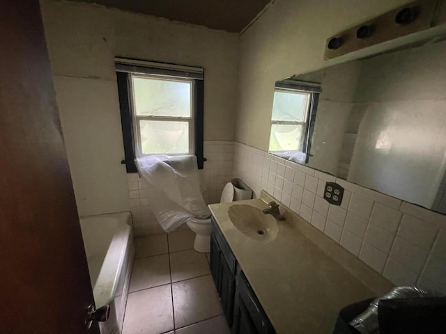 bathroom featuring toilet, vanity, tile patterned floors, and a healthy amount of sunlight