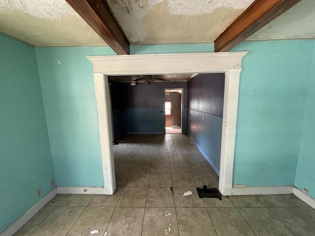 hallway with beamed ceiling, tile patterned flooring, and a textured ceiling