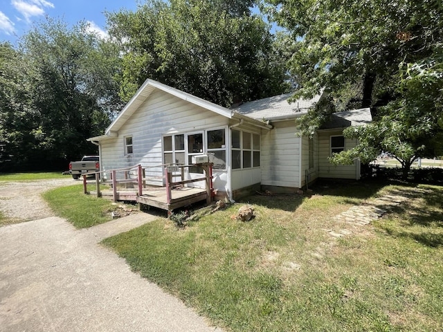 single story home with a wooden deck and a front lawn