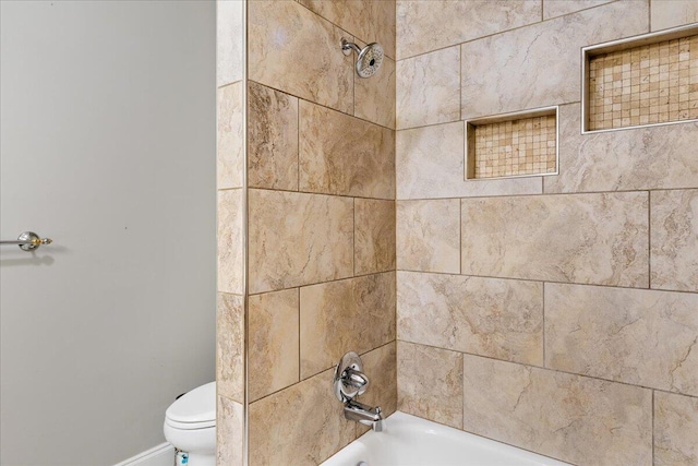 bathroom featuring tiled shower / bath combo and toilet