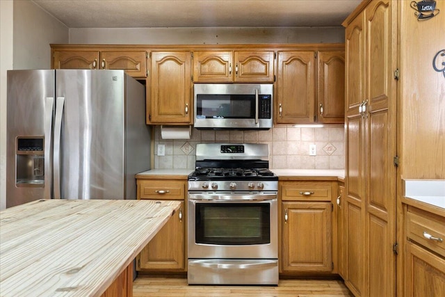 kitchen featuring light hardwood / wood-style flooring, appliances with stainless steel finishes, and tasteful backsplash