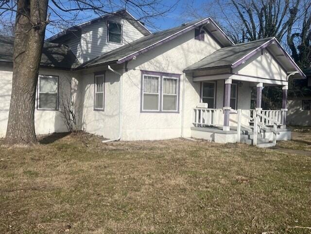 view of side of home featuring covered porch and a yard