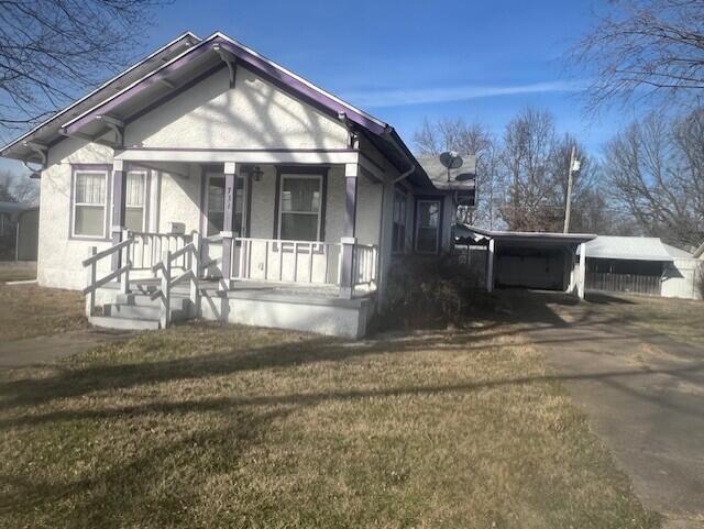 view of front of house with a front lawn, a porch, and a carport