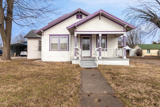 bungalow featuring a carport, covered porch, and a front lawn