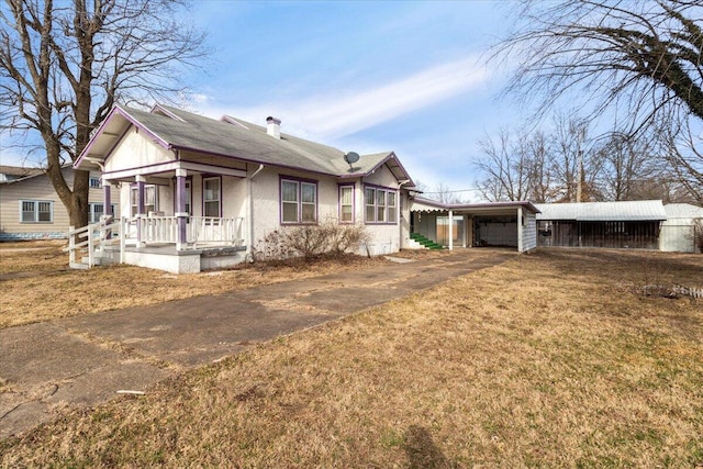 view of front of house featuring a carport, covered porch, and a front lawn