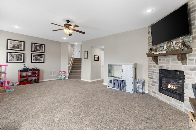 unfurnished living room featuring carpet flooring, a stone fireplace, and ceiling fan