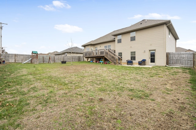 rear view of property featuring a playground, a wooden deck, a patio area, and a yard