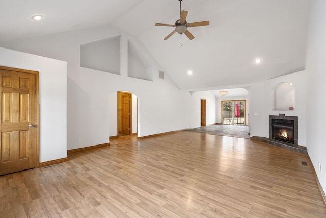 unfurnished living room featuring a fireplace, light hardwood / wood-style floors, high vaulted ceiling, and ceiling fan