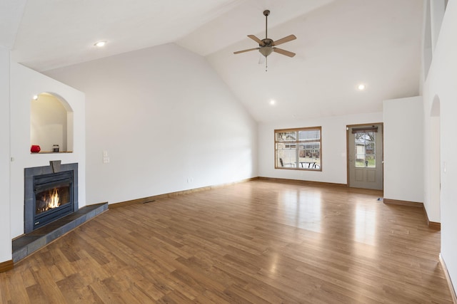 unfurnished living room with ceiling fan, wood-type flooring, a tile fireplace, and lofted ceiling