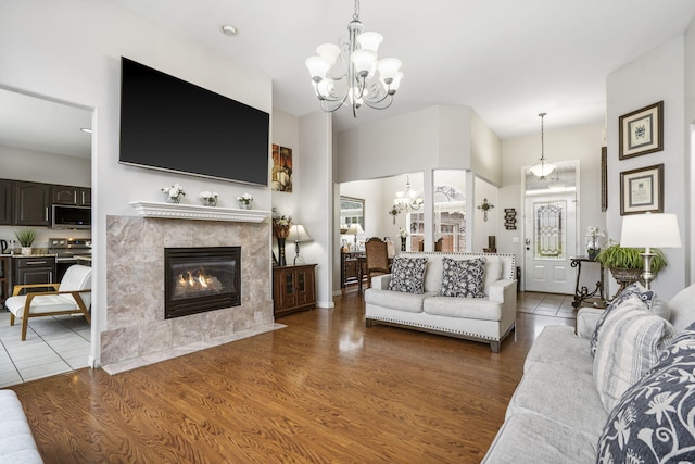 living room featuring a premium fireplace, hardwood / wood-style floors, and an inviting chandelier