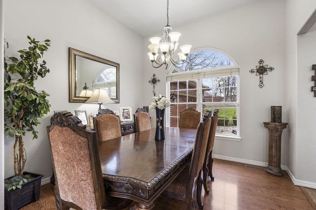 dining room with dark hardwood / wood-style flooring and an inviting chandelier