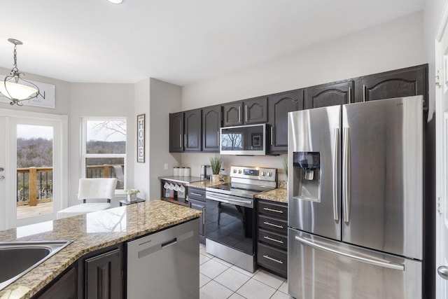 kitchen with sink, hanging light fixtures, appliances with stainless steel finishes, light tile patterned flooring, and light stone counters