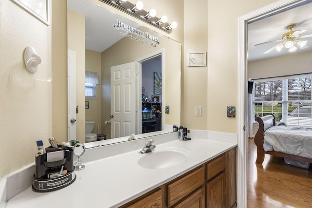 bathroom featuring wood-type flooring, vanity, toilet, and ceiling fan