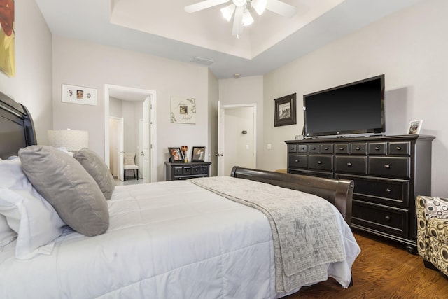 bedroom featuring a raised ceiling, connected bathroom, ceiling fan, and dark hardwood / wood-style flooring