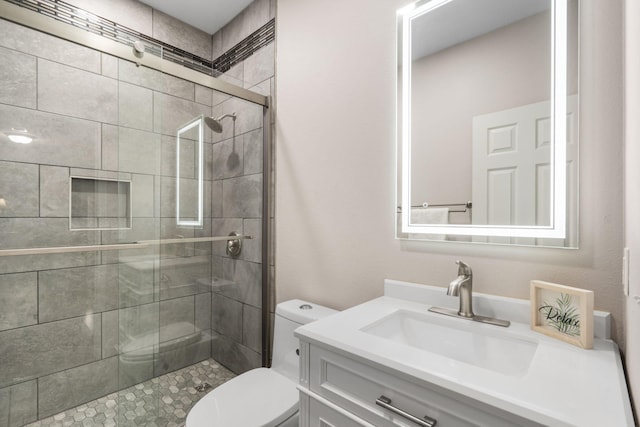 bathroom featuring vanity, a shower with shower door, and toilet