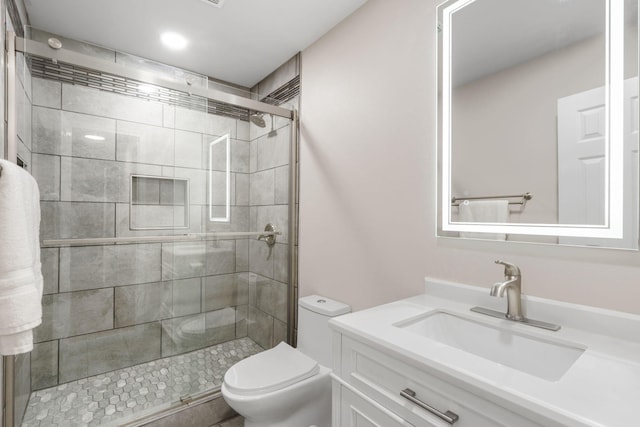 bathroom featuring vanity, a shower with shower door, and toilet