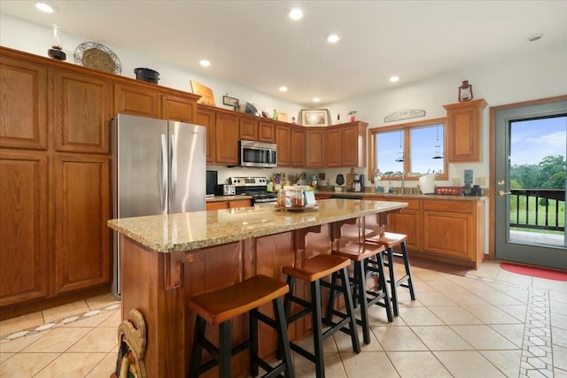 kitchen featuring a breakfast bar, a center island, sink, light tile patterned floors, and stainless steel appliances