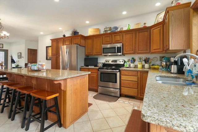 kitchen with a center island, an inviting chandelier, sink, light tile patterned floors, and appliances with stainless steel finishes