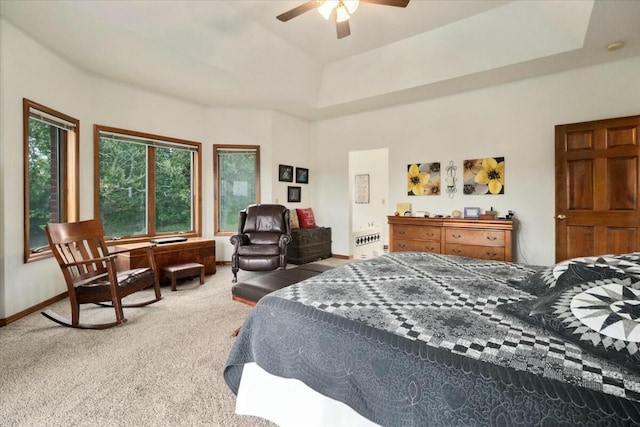 carpeted bedroom featuring a raised ceiling and ceiling fan