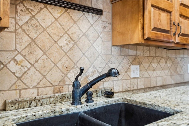 details with tasteful backsplash, light stone countertops, and sink