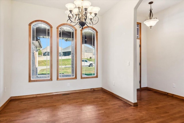 unfurnished dining area featuring dark hardwood / wood-style flooring and a notable chandelier