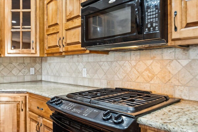 kitchen with tasteful backsplash, light stone counters, and black appliances