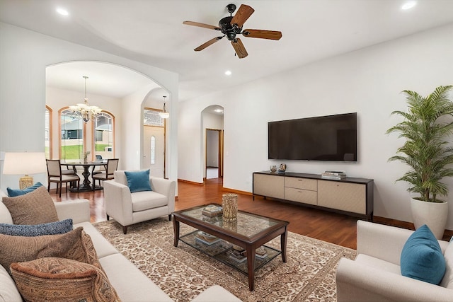 living room with dark hardwood / wood-style floors and ceiling fan with notable chandelier