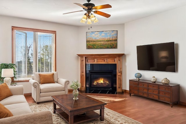 living room featuring light hardwood / wood-style floors, a tile fireplace, and ceiling fan