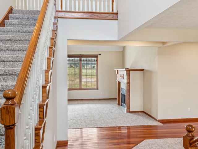 staircase with a towering ceiling and hardwood / wood-style flooring