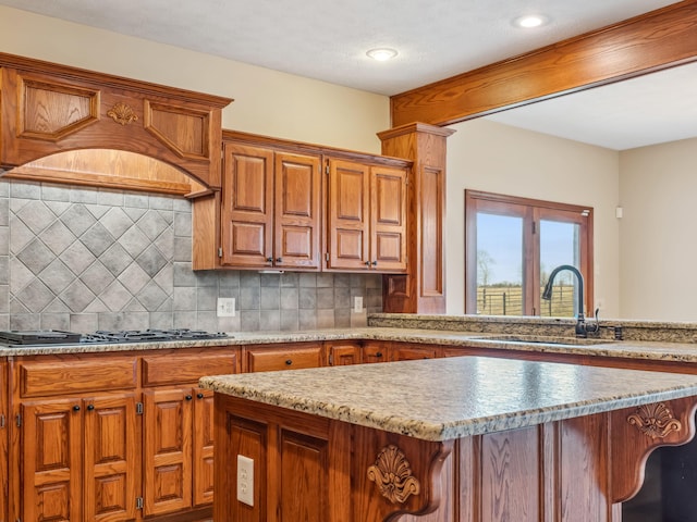 kitchen featuring decorative backsplash, gas cooktop, custom range hood, sink, and a kitchen island