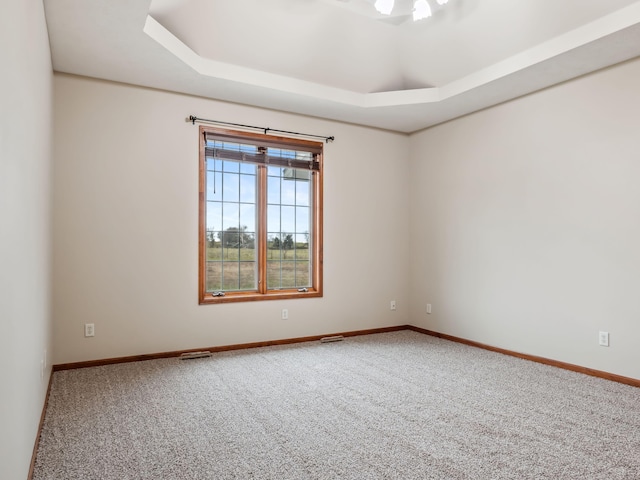 carpeted empty room with a tray ceiling