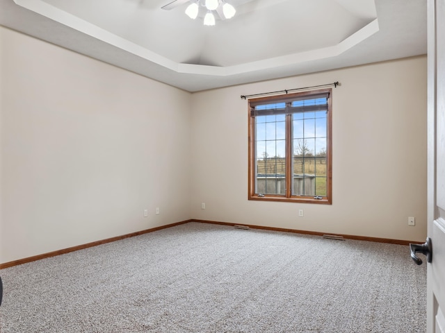 unfurnished room featuring a tray ceiling, ceiling fan, and carpet